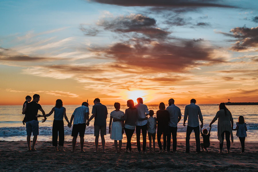 Família reunida de mãos dadas na praia ao pôr do sol